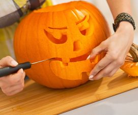 Closeup on housewife carving a big orange pumpkin Jack-O-Lantern